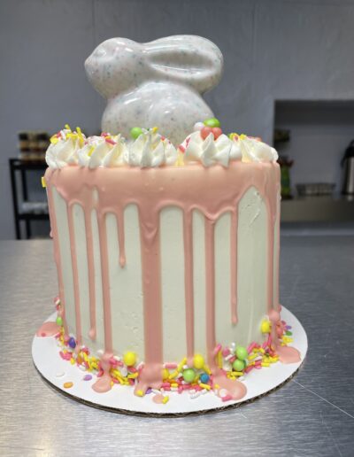 white cake with pink drip edge decorated with a white rabbit on the top