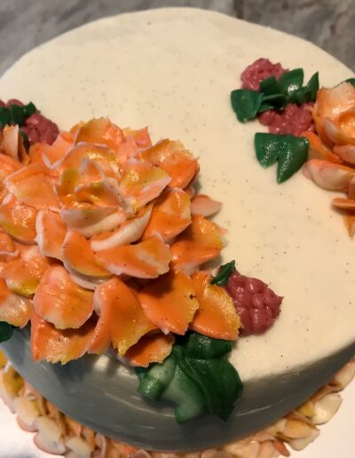 image of a round cake with two orange flowers on top